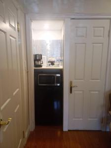 een keuken met een witte deur en een magnetron bij Lakeside executive suite small room in Tottenham