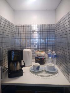 een aanrecht met een koffiezetapparaat en koffiekopjes bij Lakeside executive suite small room in Tottenham