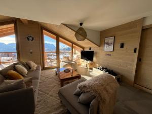 a living room with couches and a television and mountains at La Terrasse de l Alpe d Huez in L'Alpe-d'Huez