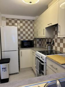 a kitchen with white cabinets and a white refrigerator at Cosy Corner - 2 beds, free parking, garden, 2 mins walk to Southampton General Hospital in Southampton