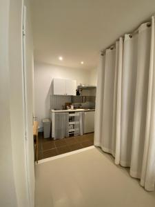 uma cozinha com paredes brancas e cortinas num quarto em Joli studio centre historique et au calme (2) em Montpellier