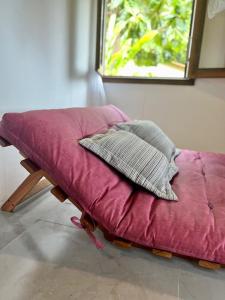 - un futon avec 2 oreillers devant une fenêtre dans l'établissement Casa do João, à Île de Boipeba