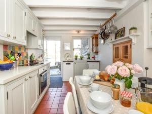 a kitchen with white cabinets and a table with flowers on it at 3 Bed in Polruan PC009 in Fowey