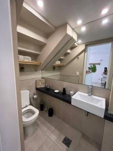 een badkamer met een toilet, een wastafel en een spiegel bij Departamento San Isidro con Luz, Aire y Verde in San Isidro
