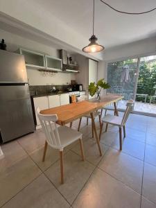 een keuken met een houten tafel en witte stoelen bij Departamento San Isidro con Luz, Aire y Verde in San Isidro