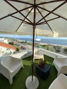 eine Terrasse mit zwei weißen Stühlen und einem Sonnenschirm in der Unterkunft Hotel Vista La Floresta in La Floresta