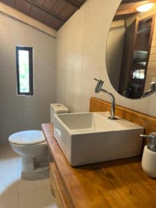 a bathroom with a sink and a toilet and a mirror at Casa do João in Ilha de Boipeba