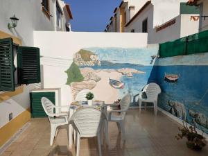a table and chairs in front of a wall with a mural at Lodge & Hike Almograve 2 in Almograve