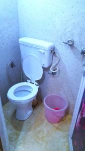 a bathroom with a toilet and a pink bucket at Goroomgo Comfort Hostel Charbagh Lucknow Near Railway Station in Lucknow
