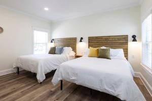 two beds in a bedroom with white walls and wooden floors at Newcastle 106 Inn at Old Beach in Virginia Beach