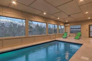 uma piscina com duas cadeiras verdes num quarto em Clear Blue Morning - Heated Pool & Cinema Nights em Sevierville