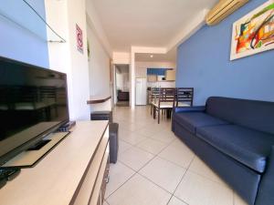 a living room with a blue couch and a television at Apart Hotel Margherita in Natal