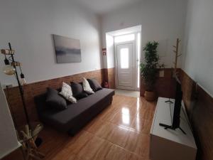 un soggiorno con un divano e una televisione di Casa da Madalena a Faro