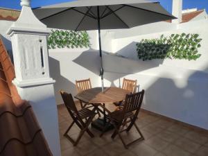 un tavolo e sedie con un ombrellone in un patio di Casa da Madalena a Faro
