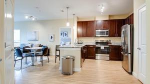 Landing Modern Apartment with Amazing Amenities (ID7221X88) في فريدريك: مطبخ بدولاب خشبي وطاولة مع كراسي