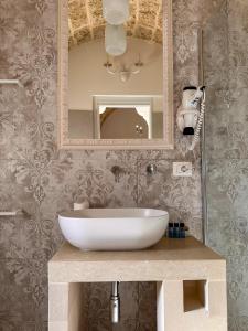 a bathroom with a white sink and a mirror at Palazzo Alma luxury rooms in Casarano