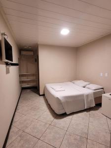 a bedroom with a bed and a tv in it at Happy Inn Hotel in Jaguariúna