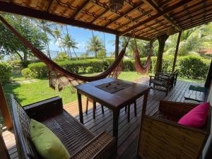 a porch with a hammock and a table and chairs at Casa do Balanço in Ilha de Boipeba