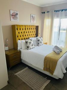 a bedroom with a large bed with a yellow headboard at Winbert Apartments in Ladysmith