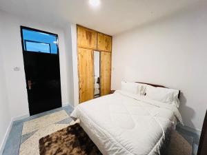 a bedroom with a white bed and a black door at Urban Haven -Entire Apartment in Iringa +20 photos