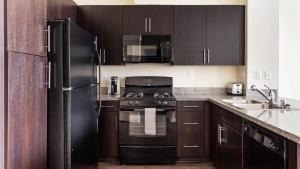 una cocina con electrodomésticos negros y armarios de madera en Landing Modern Apartment with Amazing Amenities (ID6986X77), en Otay Mesa