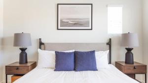 1 dormitorio con 1 cama con almohadas azules y 2 lámparas en Landing Modern Apartment with Amazing Amenities (ID6986X77), en Otay Mesa