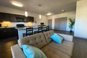 a living room with a couch and a kitchen at KING BEDS-Lg Apt-65 inch Roku-Walk to Food and Drinks in Fort Worth