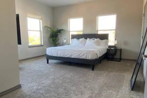 a bedroom with a large bed with white sheets and pillows at KING BEDS-Lg Apt-65 inch Roku-Walk to Food and Drinks in Fort Worth