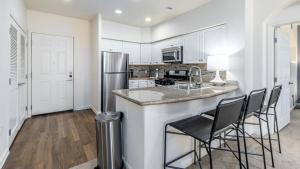 a kitchen with white cabinets and a counter with bar stools at Landing Modern Apartment with Amazing Amenities (ID5499X01) in San Diego