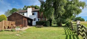 a house with a wooden fence and a tree at Wild Spa Cottage in Southwater