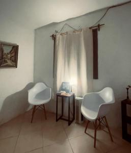 duas cadeiras brancas sentadas numa sala com uma mesa em El Bosque +598 94625953 em Parque del Plata