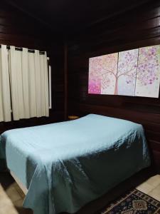 ein Schlafzimmer mit einem Bett mit zwei Monitoren an der Wand in der Unterkunft Chalé Manacá House in Campos do Jordão