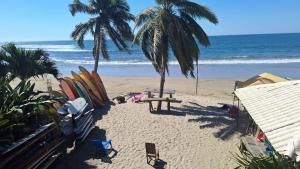 a beach with palm trees and a picnic table and surfboards at Chuchosmom room 3 in Temalhuacán
