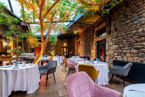 a restaurant with tables and chairs and a stone wall at Chez Camille in Arnay-le-Duc