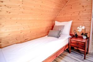 Bett in einem Zimmer mit einer Holzwand in der Unterkunft Ośrodek Wypoczynkowy IDA in Mielenko