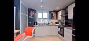 a kitchen with white cabinets and an orange chair at Apartment in Scottish Borders in Jedburgh