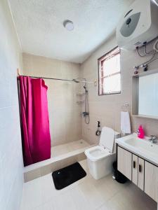baño con cortina de ducha rosa y aseo en Urban Haven -Entire Apartment, en Iringa
