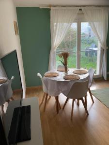 d'une salle à manger avec une table, des chaises et une fenêtre. dans l'établissement Appartement Port-En-Bessin Mer Proche, à Port-en-Bessin-Huppain