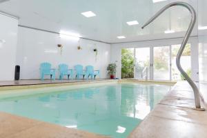 a swimming pool with blue chairs in a building at Hotel Vista La Floresta in La Floresta