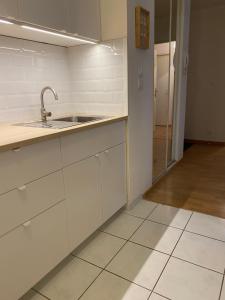 - une cuisine avec des placards blancs, un évier et une porte dans l'établissement Appartement Port-En-Bessin Mer Proche, à Port-en-Bessin-Huppain