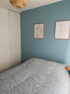 - une chambre avec un lit et deux photos sur le mur dans l'établissement Appartement Port-En-Bessin Mer Proche, à Port-en-Bessin-Huppain