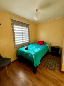 a bedroom with a bed with a green blanket and a window at Cabañas Ruta Lacustre in Licán Ray