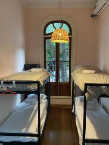 um quarto com 3 beliches e uma janela em La casona de Palermo Hostel Boutique em Buenos Aires