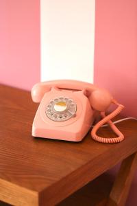różowy telefon siedzący na drewnianym stole w obiekcie Hotel Casarose - Cannes Mandelieu w mieście Mandelieu-la-Napoule