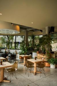 een restaurant met tafels, stoelen en planten bij The Somos Flats Central Poblado in Medellín