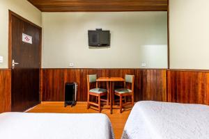 a bedroom with a table and a tv on the wall at Pousada Saint Gallen in Campos do Jordão