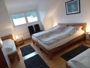 a bedroom with a large bed and two windows at Haus Lucia, mit Pool und Sauna, Appartment 4 in Schonwald im Schwarzwald