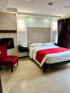 a bedroom with a large bed and a red chair at Hotel Imperial in Ambato