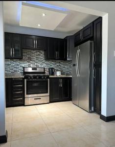 uma cozinha com armários pretos e um frigorífico de aço inoxidável em The Jewel em Kingston