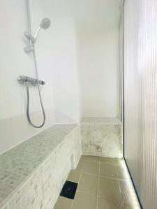 a shower in a bathroom with a tiled floor at L'Estagnole pour 2 personnes, jacuzzi, hammam in Estaing +8 photos
